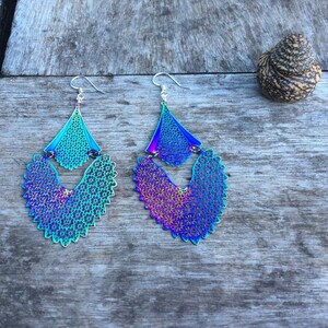 May include: A pair of iridescent blue and purple dangle earrings with a delicate, intricate design. The earrings are made of metal and have a silver-toned finish.
