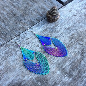 May include: A pair of iridescent earrings with a floral design. The earrings are made of metal and have a silver hook.