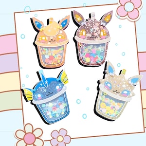 May include: Four colorful resin charms shaped like Pokemon characters in a bubble tea cup. Each charm has glitter and colorful sprinkles inside the cup.