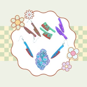 May include: A set of colorful knife-shaped earrings with glitter accents. The earrings are in the shape of a butcher knife, a chef's knife, and a small knife. There is also a small blue and purple charm with a face on it.