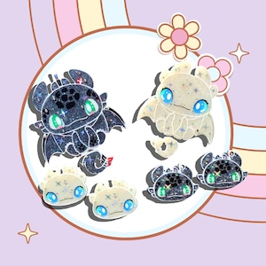 Pode incluir: Um conjunto de seis pingentes de dragão de glitter preto e branco. Os dragões estão em várias poses, incluindo voar, sentar e ficar em pé. Os pingentes são perfeitos para adicionar um toque de fantasia a joias, chaveiros ou outras manualidades.