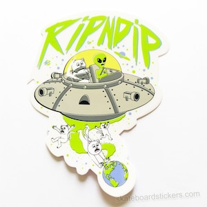 Pode incluir: Um alienígena verde em um disco voador com a palavra "RIPNDIP" em letras verdes. O disco voa sobre uma Terra azul e verde com três gatos brancos caindo do disco.