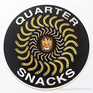 Puede incluir: Una pegatina redonda negra y dorada con las palabras "Quarter Snacks" y un logotipo de calavera en llamas en el centro. La pegatina tiene un diseño de eslabón de cadena alrededor del borde.
