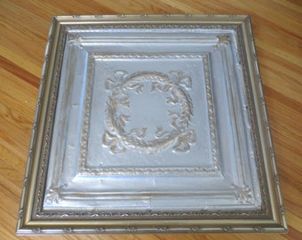 FRAMED ANTIQUE CEILING Tile 28" x 28" In Goltone Wood Frame, The TIle Is Silver And Gold Wreath With Bow Design