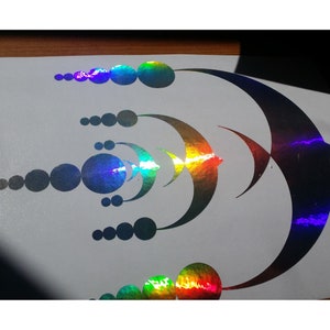 Könnte beinhalten: Ein holografischer Aufkleber mit einem geometrischen Design, das aus einer Reihe von Kreisen und Halbmondformen besteht. Der Aufkleber hat eine regenbogenfarbene, irisierende Oberfläche.