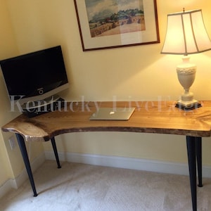 May include: A wooden desk with a live edge top and black metal legs. A laptop computer and a lamp are on the desk.