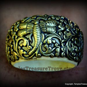 Puede incluir: Un brazalete de oro y marfil con un intrincado diseño floral y un motivo de libélula. El brazalete está hecho de hueso y metal.
