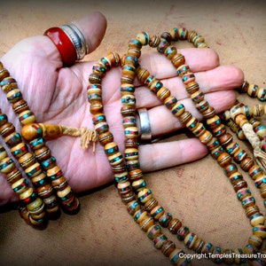 May include: Four strands of prayer beads made of bone with turquoise and red accents. The beads are strung on a cord with a tassel at the end.