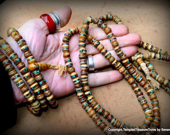 May include: Four strands of prayer beads made of bone with turquoise and red accents. The beads are strung on a cord with a tassel at the end.