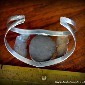 Puede incluir: Pulsera de plata con una gran piedra ovalada de turquesa engastada en un engaste de plata. La pulsera est&aacute; decorada con filigrana de plata y tiene una marca estampada en la parte posterior.