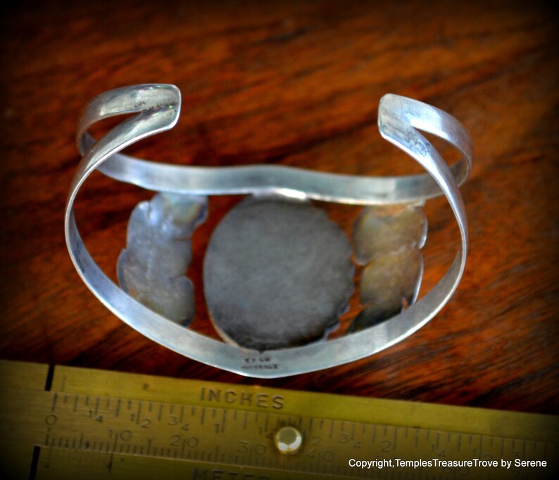 Puede incluir: Pulsera de plata con una gran piedra ovalada de turquesa engastada en un engaste de plata. La pulsera est&aacute; decorada con filigrana de plata y tiene una marca estampada en la parte posterior.