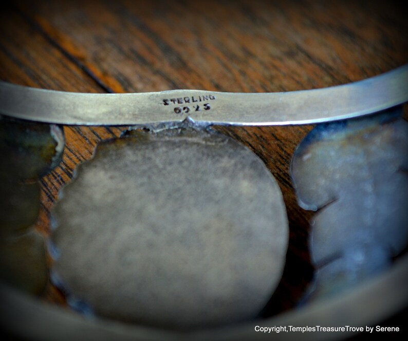 Puede incluir: Una pulsera de plata con un dise&ntilde;o floral y la inscripci&oacute;n "STERLING 925" en la parte posterior.