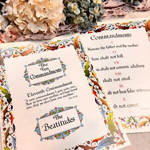 May include: Two open pages with text from the Bible, including "The Ten Commandments" and "The Beatitudes." The pages are decorated with colorful borders and floral accents. A bouquet of flowers is in the background.