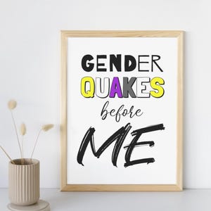 Könnte beinhalten: Ein rechteckiger Holzrahmen mit einem weißen Druck, der den schwarzen Text GENDER, das Wort QUAKES in Gelb, Lila, Grau und Weiß, das Wort before in schwarzer Schreibschrift und das Wort ME in großen, fetten, schwarzen Pinselstrichen zeigt.