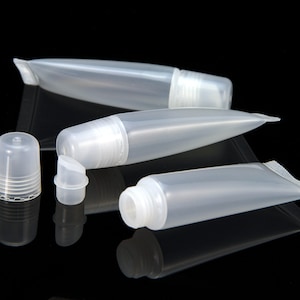 Può includere: Tre tubi di plastica trasparente con tappi a vite. I tubi sono vuoti e sono su una superficie nera.