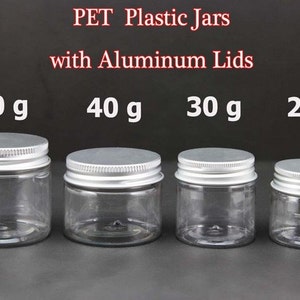 Op de afbeelding: Vier doorzichtige plastic potten met zilveren aluminium deksels. De potten zijn gelabeld met de volgende gewichten: 50 g, 40 g, 30 g en 25 g.