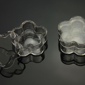 May include: Three clear plastic flower-shaped containers with lids. The containers are stacked on top of each other.