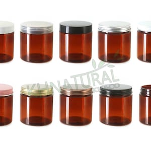 Op de afbeelding: Tien amber glazen potten met verschillende gekleurde deksels. De deksels zijn wit, zilver, zwart, goud en roze. De potten zijn allemaal even groot en hebben dezelfde vorm.