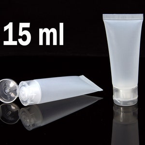 May include: Two clear plastic squeeze bottles with flip top caps. The bottle on the left is lying down with the cap open. The bottle on the right is standing upright. Both bottles are 15 ml.