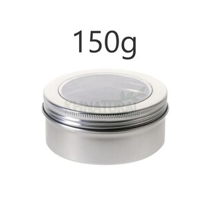 Pode incluir: Um recipiente de metal prateado com uma tampa transparente. O recipiente está etiquetado com "150g".