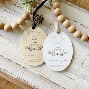May include: Two wooden ornaments featuring a house design, the text "Our First Home" and the year "2021". The ornaments are personalised with the names "Mekayla & John" and the address "2340 East Walter Ave, Montgomery Alabama".