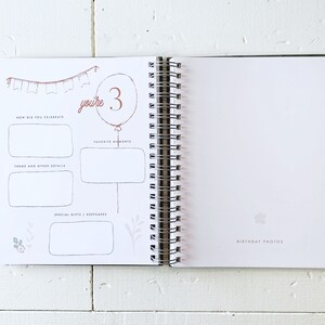 May include: A white page with a pink and brown illustration of a birthday party with the text "you're 3". The page has sections for "How did you celebrate", "Theme and other details", "Favorite moments", and "Special gifts/keepsakes".