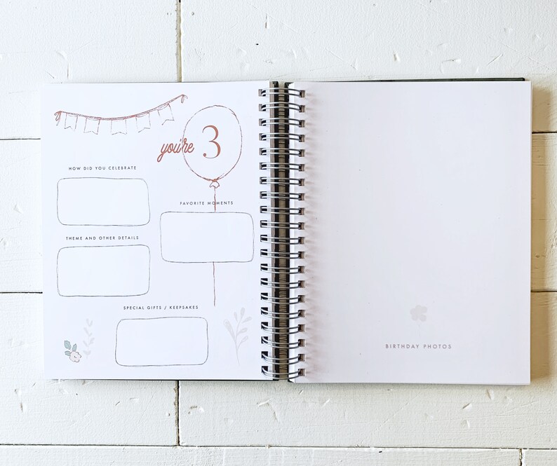 May include: A white page with a pink and brown illustration of a birthday party with the text "you're 3". The page has sections for "How did you celebrate", "Theme and other details", "Favorite moments", and "Special gifts/keepsakes".