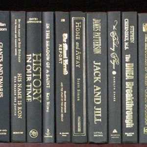 Puede incluir: Una estanter&iacute;a de libros negros con letras doradas en los lomos. Los t&iacute;tulos incluyen "Culturally Incorrect Parsley", "Giants and Dwarfs", "His Name Is Ron", "History in Our Time", "In the Shadow of a Saint", "The Miami Herald Report", "Home and Away", "Jack and Jill", "The DHEA Breakthrough", "The Seduction of Water" y "Hi Cooking with Regis & Kathie Lee".