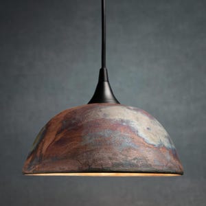 May include: A pendant light fixture with a dome-shaped shade. The shade has a mottled appearance with shades of brown, red, and blue. The fixture has a black stem and a black conical top.