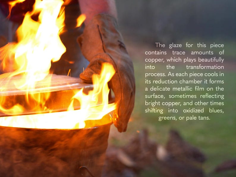 May include: A ceramic vessel being removed from a fire, featuring a glaze with copper that creates metallic films in shades of blue, green, and tan. The text reads: The glaze for this piece contains trace amounts of copper, which plays beautifully into the transformation process. As each piece cools in its reduction chamber it forms a delicate metallic film on the surface, sometimes reflecting bright copper, and other times shifting into oxidized blues, greens, or pale tans.