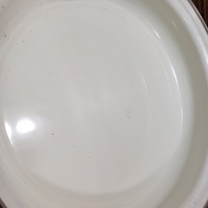 May include: White enamel baking dish with a slightly rounded rim. The dish is empty and clean.