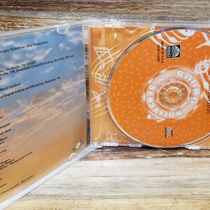 May include: A clear plastic CD case with a CD inside. The CD is orange with white text that reads "Kenny Rogers Love Collection". The case is open, revealing the CD and the album's liner notes.