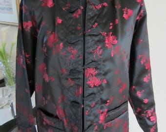 May include: A black satin jacket with a red floral pattern and frog closures. The jacket has a mandarin collar and long sleeves.