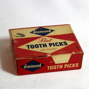 May include: A red and white cardboard box with the words "Diamond Flat Tooth Picks" and "750 Count" printed on it. The box is labeled "White Birch" and has a blue diamond logo with the word "Diamond" printed on it.