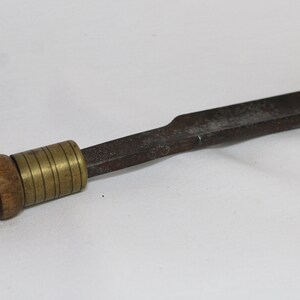 May include: A wooden handled tool with a brass adjustable collar and a flat, metal blade. The blade is slightly curved and has a dull finish.