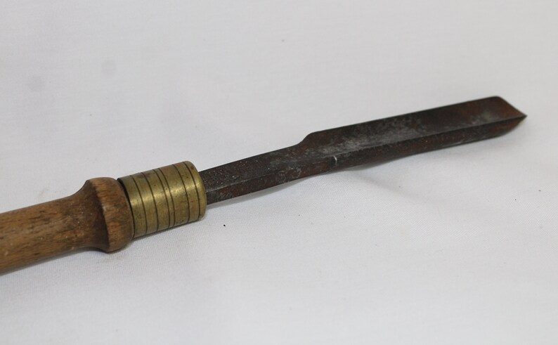 May include: A wooden handled tool with a brass adjustable collar and a flat, metal blade. The blade is slightly curved and has a dull finish.