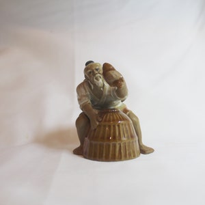 Pescatore cinese shiwan mudman vintage con un cestino da pesca che tiene un pesce
