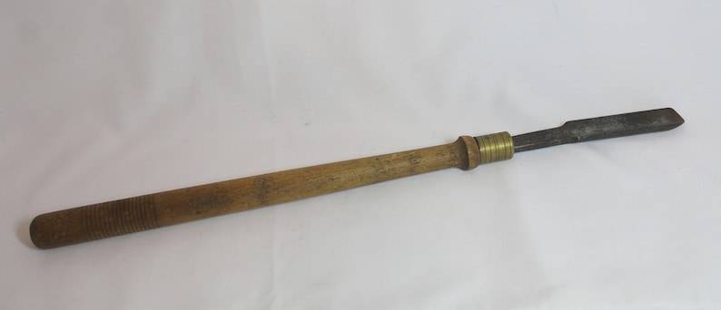 May include: A wooden handled wood carving tool with a brass ferrule and a metal blade.
