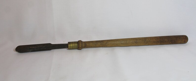 May include: A wooden handled metal tool with a brass ferrule. The tool has a flat, rectangular blade.