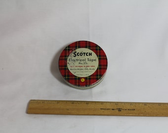 May include: A round tin of Scotch Electrical Tape No. 33. The tin is red and black plaid with white lettering. The text reads "Scotch Electrical Tape No. 33 The Work of 3M Tapes Resists Water, Oils, Acids 1 Roll No. 33 3/4 in x 66 ft."