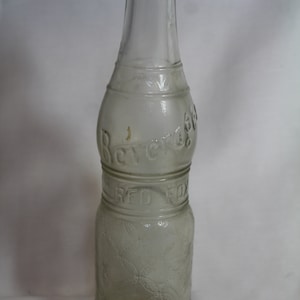 May include: A clear glass bottle with a textured surface. The bottle has the words "Beverage Co." and "Red Fox" embossed on it.