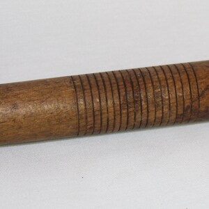 May include: A wooden rolling pin with a textured surface. The rolling pin is brown and has a smooth, rounded handle.