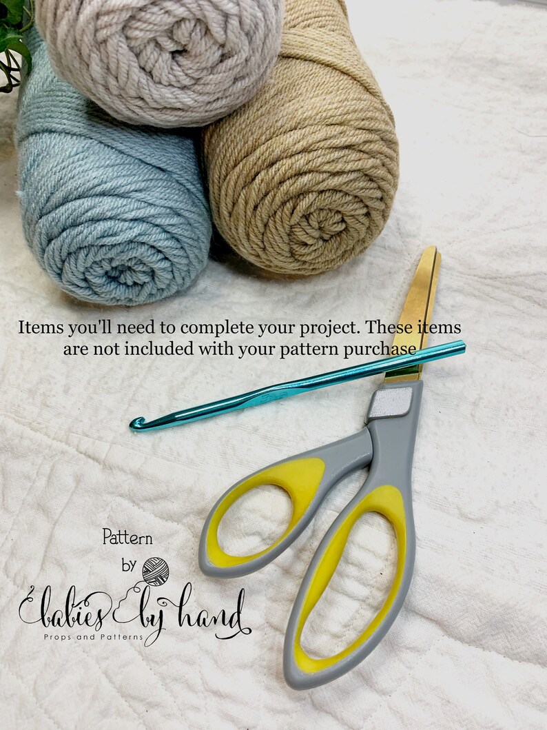 May include: Three balls of yarn in beige, light blue, and gray, a pair of yellow-handled scissors, and a turquoise crochet hook. The text "Pattern by Babies by Hand Props and Patterns" is at the bottom of the image.