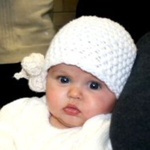 May include: A white crocheted baby hat with a white crocheted flower on the side.