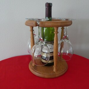 May include: Wooden wine rack with four glass holders and a bottle of wine. The rack is made of natural wood and has a rustic look.