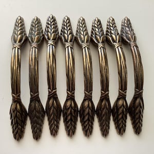 May include: A white ceramic mug with a black handle and the text "But First, Coffee" in a bold, black font. The mug is set against a blurred background, suggesting a cozy setting. The mug appears to be approximately 4 inches tall.