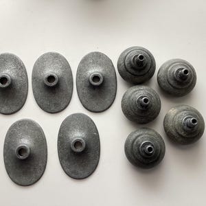 May include: A white ceramic mug with a black handle and the text "But First, Coffee" in a bold, black font. The mug is set against a blurred background, suggesting a cosy setting.