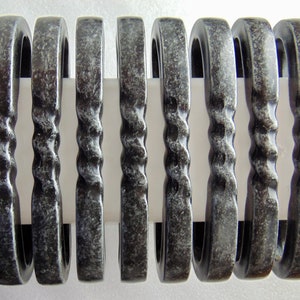 May include: Eight silver-toned metal curtain tiebacks with a twisted design. The tiebacks are arranged in a row and are all the same size and shape.