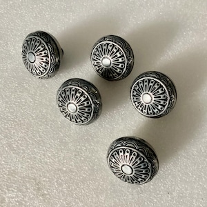 May include: Five silver-toned metal buttons with a decorative, circular design. Each button features a raised, concentric circle pattern with a smaller, white circle in the center.