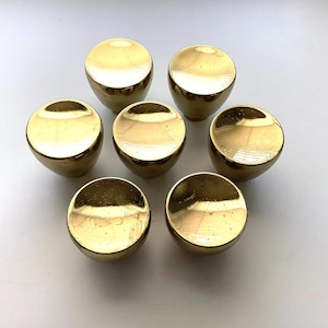 May include: A white ceramic mug with a black handle and the text "But First, Coffee" in a bold, black font. The mug is set against a blurred background, suggesting a cozy setting.